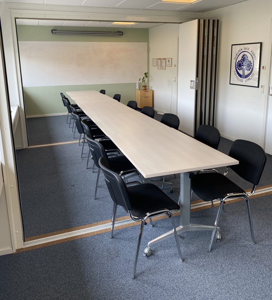 Mødelokale med whiteboard, lærred til projektor, fire mødeborde og 14 stole